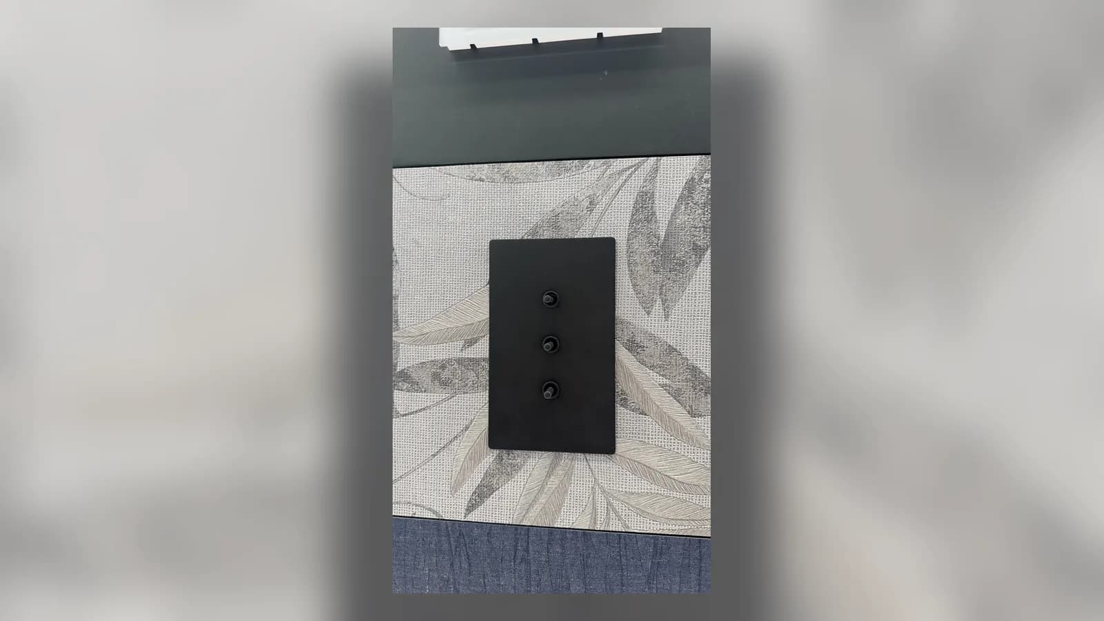 لوحة مفاتيح Lutron سوداء بثلاثة أزرار مثبتة على ورق جدران منقوش