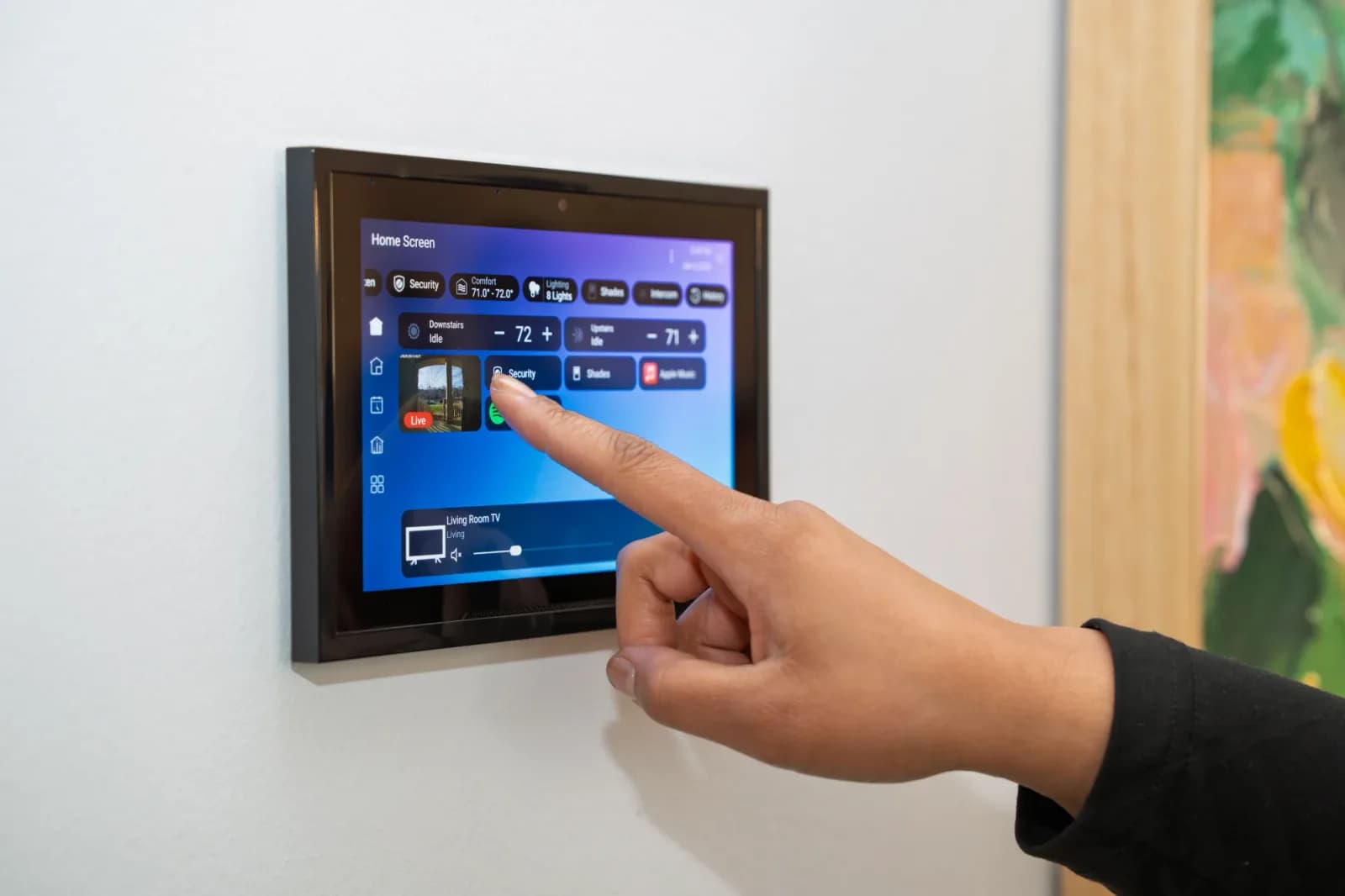 Wall-mounted touch screen showing a home control screen with security, comfort, lighting and shades
