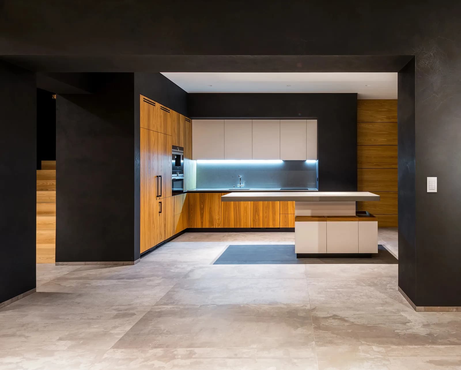 Dark kitchen with timber cabinets, under-cabinet lighting and a wall keypad